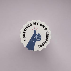 Könnte beinhalten: Ein weißer Aufkleber mit gewelltem Rand und dem Text "I SURVIVED MY DM'S CAMPAIGN!", der eine blaue Daumen-hoch-Illustration mit roten Akzenten umkreist. Der Aufkleber ist auf einem hellvioletten Hintergrund zentriert.