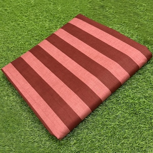 May include: A rectangular piece of fabric featuring a repeating pattern of wide, alternating stripes in dark maroon and light coral pink. The textile has a visible woven texture and is folded into a neat, flat shape with clean, straight edges.