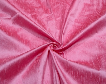 May include: A close-up of a pink silk fabric with a subtle sheen. The fabric is draped and folded, creating soft, flowing lines.