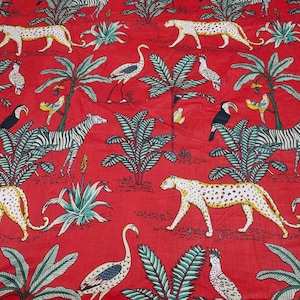 Puede incluir: Tela roja con un estampado de temática selvática. El diseño presenta cebras, leopardos, tucanes y otras aves entre palmeras y follaje exuberante. La tela tiene un diseño vibrante y llamativo.