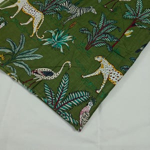 Peut inclure: Tissu vert avec un imprimé sur le thème de la jungle, représentant des léopards, des zèbres, des oiseaux et un feuillage luxuriant. Le motif comprend des motifs d'animaux blancs, jaunes et noirs, et diverses nuances de vert.