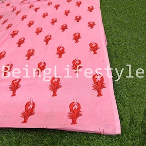 Puede incluir: Tela rosa con un patr&oacute;n repetido de langostas rojas. El texto "BeingLifestyle" est&aacute; impreso en blanco en la tela. La tela est&aacute; doblada y parcialmente visible.