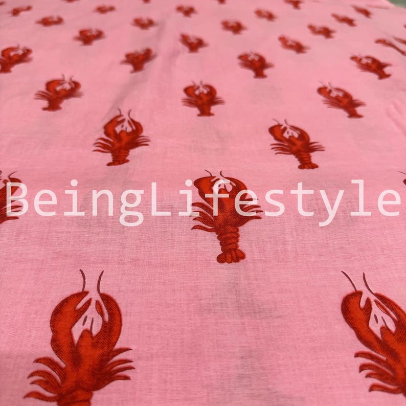 Puede incluir: Tela rosa claro con un patr&oacute;n repetido de langostas rojas. El texto blanco "BeingLifestyle" est&aacute; impreso en la tela. Adecuado para ropa o decoraci&oacute;n del hogar.