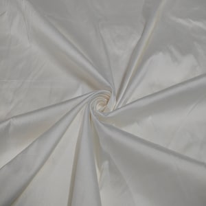 Puede incluir: Tela blanca con una textura suave y sedosa. La tela está doblada y dispuesta en espiral.