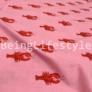 Puede incluir: Tela rosa claro con un patr&oacute;n repetido de langostas rojas. El texto "BeingLifestyle" est&aacute; impreso en la tela. La tela parece ser de algod&oacute;n, adecuada para varios proyectos de costura.
