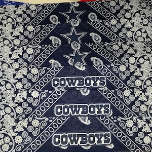 Puede incluir: Una pila de bandanas azules con un patrón de cachemira blanco. Las bandanas tienen la palabra "COWBOYS" impresa en blanco. Las bandanas también tienen un diseño de estrella blanca.