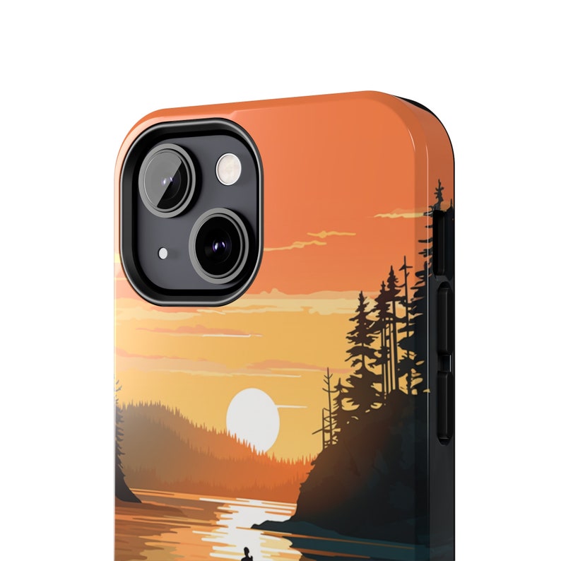 May include: A phone case with a sunset scene featuring a silhouette of trees and a lake. The case is black with a clear back panel showing the image.