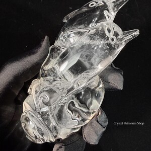 Pode incluir: Uma escultura de cristal transparente de dois golfinhos saltando da &aacute;gua. Os golfinhos s&atilde;o esculpidos de forma intrincada com detalhes, e a escultura assenta sobre uma base com padr&otilde;es de ondas rodopiantes. O cristal &eacute; transparente.