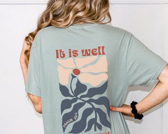 May include: A light blue t-shirt with a floral design and the text "It is well with my soul." and "Psalm 23:4" in a retro font.