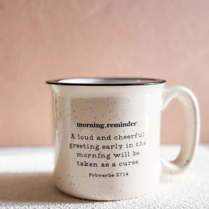 May include: White ceramic mug with a black rim and black text that reads "morning.reminder: A loud and cheerful greeting early in the morning will be taken as a curse. Proverbs 27:14"