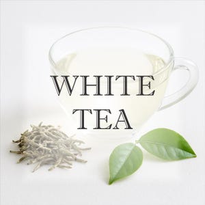 Puede incluir: Una taza de té transparente llena de té blanco, con las palabras "WHITE TEA" en texto negro. Junto a la taza hay hojas de té secas y dos hojas verdes, todo sobre una superficie blanca.