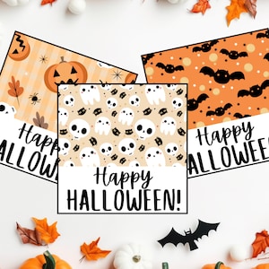 May include: Three printable Halloween gift tags with different designs. The first tag features a pumpkin, spider, and leaves on an orange and white background. The second tag features a skull, ghost, and cat on a beige background. The third tag features bats on an orange background. All three tags have the text "Happy Halloween!" on them.