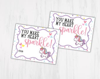 Może przedstawiać: Dwie drukowane kartki walentynkowe z jednorożcem i tekstem "You make my heart sparkle!" oraz miejscem na wpisanie "From:"
