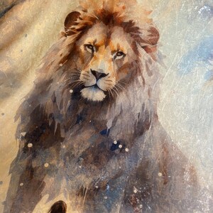 Op de afbeelding: Een aquarel van een leeuw op een gouden achtergrond. De leeuw kijkt de kijker recht aan met een serieuze uitdrukking. De schildering heeft een vintage uitstraling.