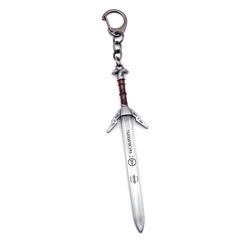 May include: A metal keychain shaped like a sword with a dark grey finish. The handle is brown with a silver pommel. The blade is silver-toned and features engraved runic symbols and a circular emblem along its length, attached to a circular ring.