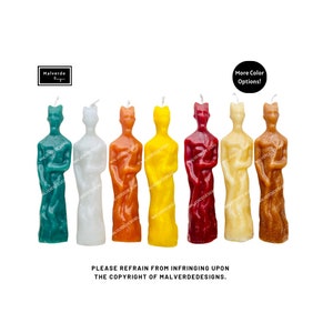 May include: Seven tall, thin, human-shaped candles in various colors: green, white, orange, yellow, red, cream, and brown. The candles are arranged in a row from left to right. The text "More Color Options!" is in a black circle at the top of the image.