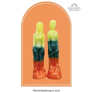 May include: Two standing human-shaped candles featuring a gradient color scheme of yellow at the top, transitioning into dark green in the middle, and ending in orange at the base. The logo Malverde Designs is visible at the top and bottom.