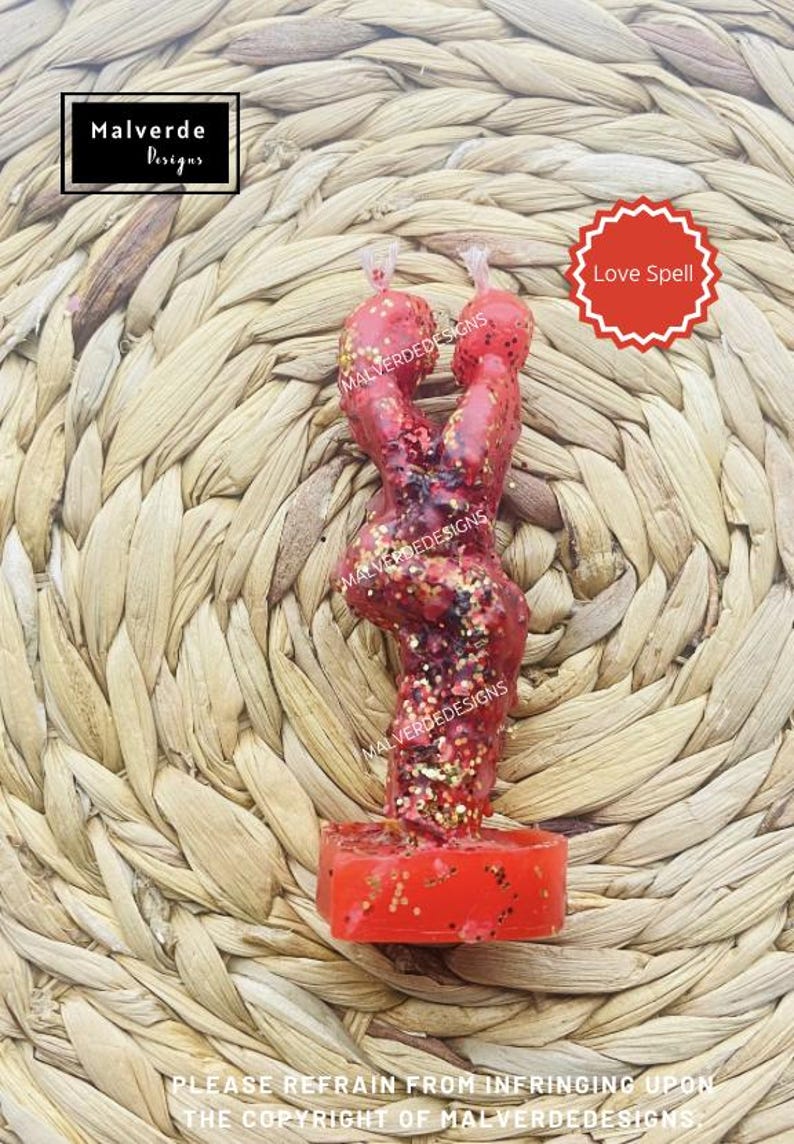 K&ouml;nnte beinhalten: Rote Liebeszauberkerze mit Glitzer, geformt wie zwei sich umarmende Figuren. Die Kerze steht auf einer gewebten Oberfl&auml;che. Der Text "Love Spell" befindet sich auf einem roten Sternensticker.
