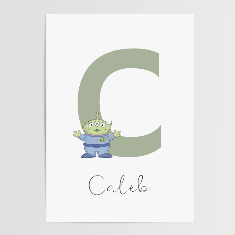 May include: A print featuring a green alien character from Toy Story, beside a large green letter "C". The name "Caleb" is written in cursive below the letter and character. The background is white.