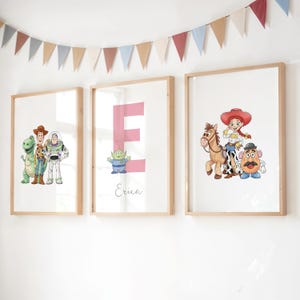 May include: Three framed prints with characters from Toy Story. One shows Woody, Buzz Lightyear, and Rex. Another has a pink letter "E" with an alien and the name "Erica". The third print shows Jessie, Bullseye, and Mr. Potato Head.