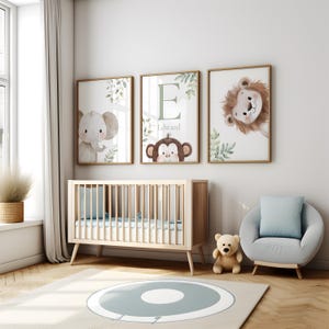 May include: Three framed nursery art prints featuring watercolor illustrations of an elephant, a monkey, and a lion. The middle print has the name "Edward" and the letter "E". A light wood crib, a teddy bear, and a round chair are in the room.
