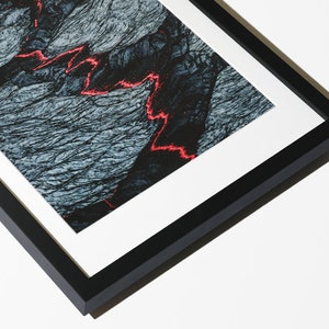 May include: A black framed photograph of a close-up of a dark gray and blue textured surface with a red line running through it.