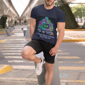 Puede incluir: Camiseta azul marino con un gráfico de neón de monitores de ordenador y el texto "SYSTEM ERROR" y "CYBERPUNK JUNKIE". La camiseta se combina con pantalones cortos negros y zapatillas blancas.