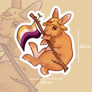 Puede incluir: Una pegatina con un conejo de dibujos animados que lleva un sombrero de pato y sostiene una bandera del orgullo no binario. El conejo es marrón con un contorno blanco. La pegatina mide 5,5 cm de ancho y 6 cm de alto.