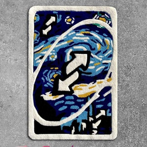 May include: A rectangular rug featuring a stylized design of an Uno reverse card, with a blue and white swirling pattern reminiscent of Van Gogh's "Starry Night." The rug has a white border and the text "The Rug Legare" in pink.