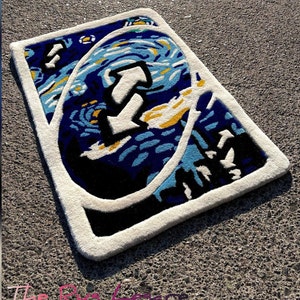 May include: A rectangular rug with a white border and a design inspired by Van Gogh's "Starry Night" painting. The rug features a large white arrow in the center, with blue, yellow, and black accents.