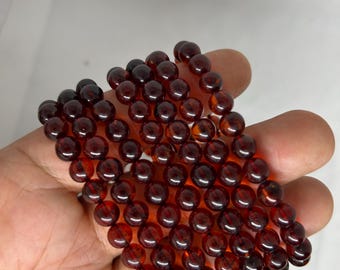 May include: A stack of six red gemstone bracelets with round beads.