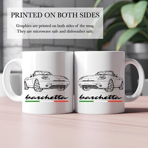 Puede incluir: Taza de cerámica blanca con una ilustración en blanco y negro de un coche descapotable Fiat Barchetta en ambos lados. La taza tiene la palabra "barchetta" impresa en negro debajo de la imagen del coche, con una franja verde, blanca y roja debajo de la palabra. El texto "IMPRESO EN AMBOS LADOS" está impreso en negro en la parte superior de la imagen. El texto "Los gráficos están impresos en ambos lados de la taza. Son aptos para microondas y lavavajillas." está impreso en negro debajo de la taza.
