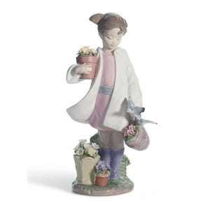 Puede incluir: Figura de porcelana de una persona joven con abrigo blanco y vestido rosa, sosteniendo una maceta y una cesta con flores. Un pájaro azul está posado en la cesta. La figura está rodeada de más macetas.