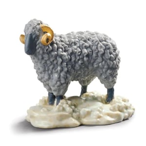 Puede incluir: Una figurita de porcelana gris de una oveja con cuernos dorados de pie sobre una base blanca.