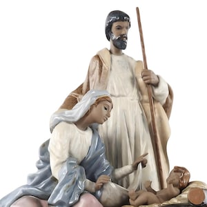 Può includere: Un presepe in ceramica raffigurante Maria, Giuseppe e Gesù bambino. Maria indossa una veste blu, Giuseppe tiene un bastone e Gesù bambino è in una mangiatoia. Le figure sono dipinte in tonalità tenui con tratti del viso dettagliati.