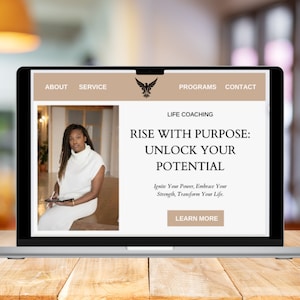 Op de afbeelding: Het scherm van een laptopcomputer waarop een website voor life coaching diensten wordt weergegeven. De website toont een zwart-witafbeelding van een vrouw die zit en een tablet vasthoudt. De tekst op de website luidt "Rise with Purpose: Unlock Your Potential. Ignite Your Power, Embrace Your Strength, Transform Your Life. Learn More."