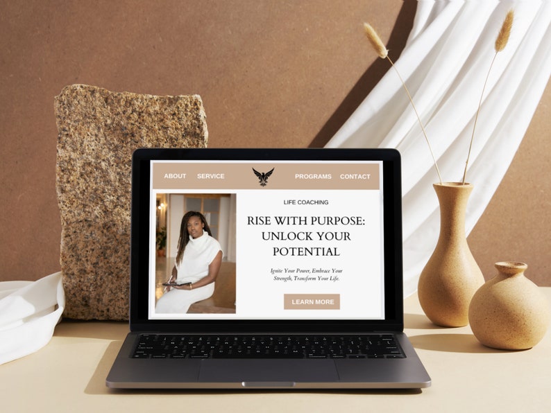Op de afbeelding: Een laptopcomputer waarop een website voor een lifecoach wordt weergegeven. De website toont een foto van een vrouw en de tekst "Rise with Purpose: Unlock Your Potential. Ignite Your Power, Embrace Your Strength, Transform Your Life. Learn More."