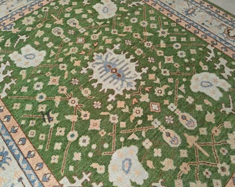 May include: A green rug with a traditional Persian design. The rug features a central medallion with intricate floral patterns and a border with geometric motifs.