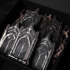 May include: A set of five black and silver gothic archway-shaped stickers in a black box with brown packing paper.