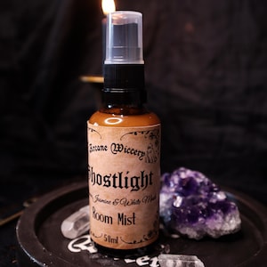 Può includere: Un flacone spray in vetro ambrato da 50ml di profumo per ambienti Ghostlight con erogatore nero. L'etichetta beige riporta il testo Arcane Wiccery, Ghostlight, Jasmine & White Musk e Room Mist in carattere nero con una piccola illustrazione di fantasma.