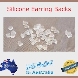 May include: A large quantity of clear silicone earring backs. The backs are small and round, and they are scattered on a white surface.