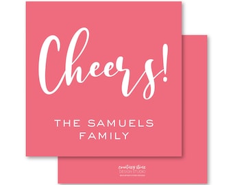 May include: Two coral-colored square cards, one slightly overlapping the other. The top card features the word "Cheers!" in white script, with "THE SAMUELS FAMILY" printed below. The bottom card is plain coral. The bottom right corner of the top card has the text "courtney stone DESIGN STUDIO".