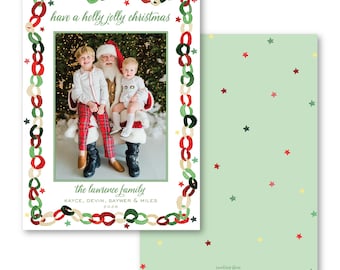 Puede incluir: Una tarjeta de felicitación navideña rectangular con una foto de dos niños y Santa Claus, enmarcada por un borde de cadenas pintadas en rojo, verde y crema. El texto dice: have a holly jolly christmas, the lawrence family, KAYCE, DEVIN, SAYWER & MILES 2026.