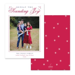 May include: A rectangular holiday card featuring a family photo of two adults and two children. The text reads Repeat The Sounding Joy, The Jones Family, Rachel, Michael, Lucy, & Beau, 2022. The back is a solid dark pink with white starbursts.