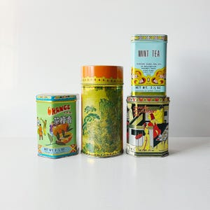 Puede incluir: Una colección de latas de té vintage de varias formas y tamaños. Las latas presentan diseños coloridos, incluyendo paisajes chinos, la marca de té de naranja y una escena de restaurante chino. La lata de té de menta es azul claro.