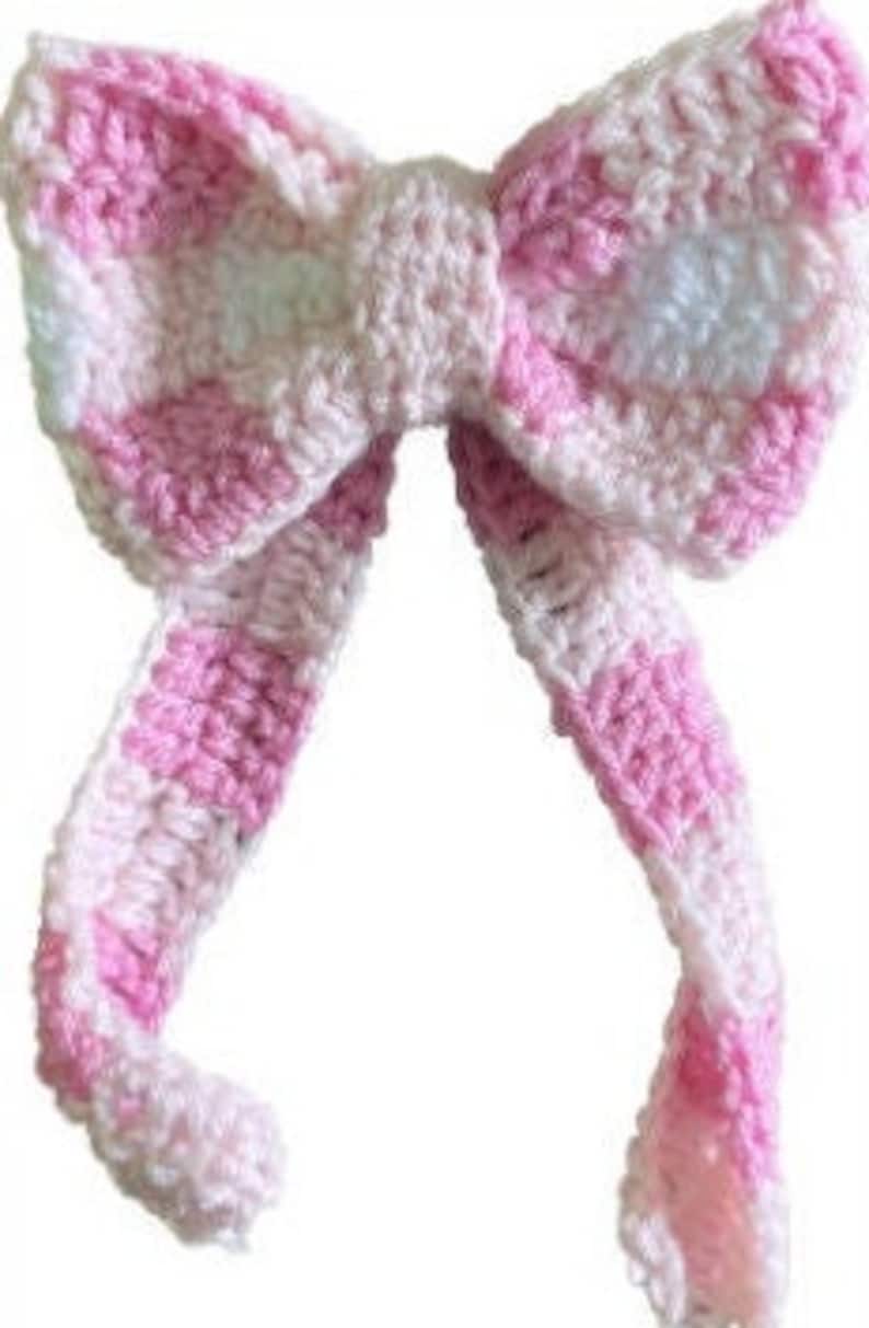 Op de afbeelding: Een roze en wit geh&auml;keld hoofdband met een gestreept patroon.