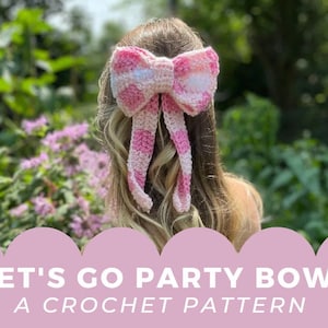 Op de afbeelding: Een roze en witte gebreide strik met een ruitpatroon. De strik is gebonden met lange linten en wordt in het haar van een meisje gedragen. De tekst "LET'S GO PARTY BOW A CROCHET PATTERN" wordt onder de afbeelding weergegeven.
