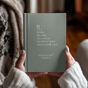May include: A sage green journal with the text "18 vote, skydive, jury duty, get a tattoo, buy lottery ticket, open a credit card. Matthew's 18th Chapter" printed in white.