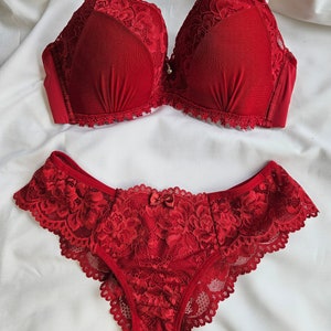 May include: Red lace lingerie set with a bra and matching panty. The bra has a delicate floral lace design and the panty has a bow detail.
