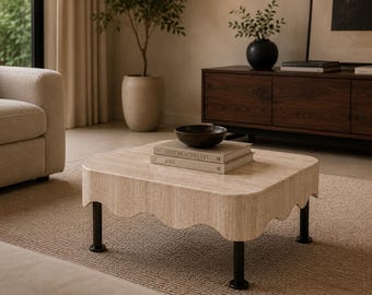 Puede incluir: Escena de salón con un sofá beige, una mesa de centro y un mueble de madera oscura. La mesa de centro tiene un diseño de borde festoneado y patas negras. Un cuenco y libros están sobre la mesa. Una alfombra cubre el suelo.